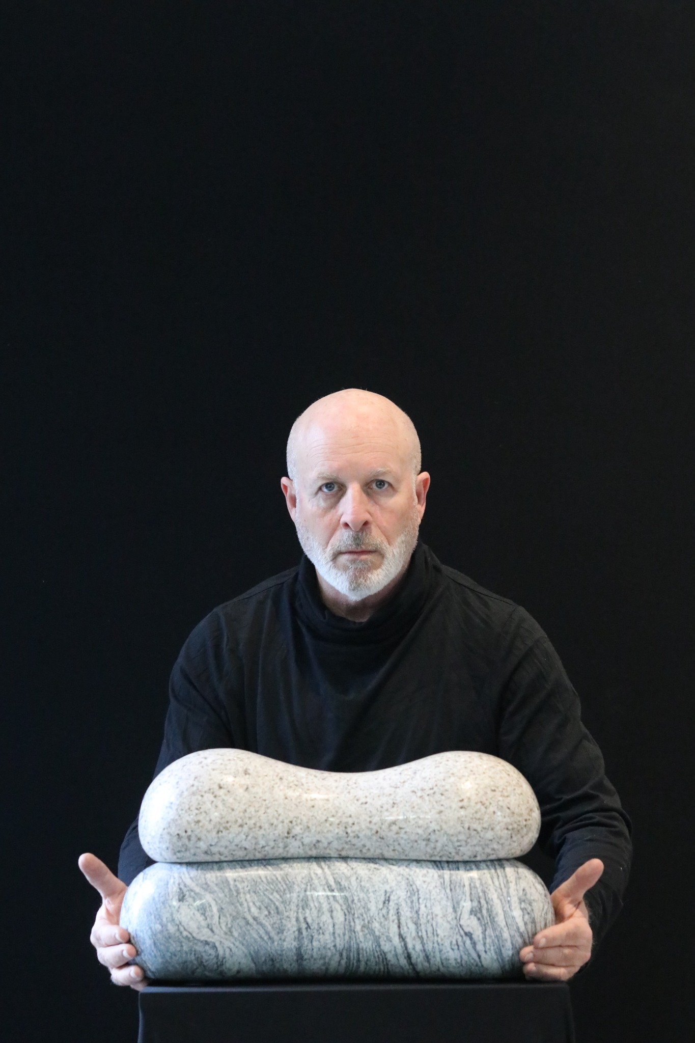 Portrait of sculptor Dan Reisner holding a stone sculpture